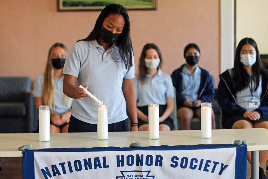 Current NHS Member Nina B. lights the ceremonial candles representing the chapter's four pillars.